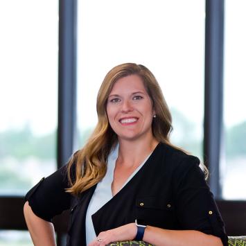 Anna Workman, posing by leaning with one elbow on a green chair.